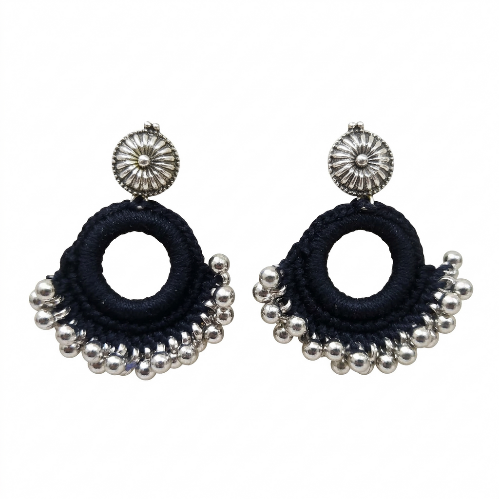 Handmade black thread crochet hoop earrings with oxidized silver floral studs and metallic ghungroo beads on a white background.