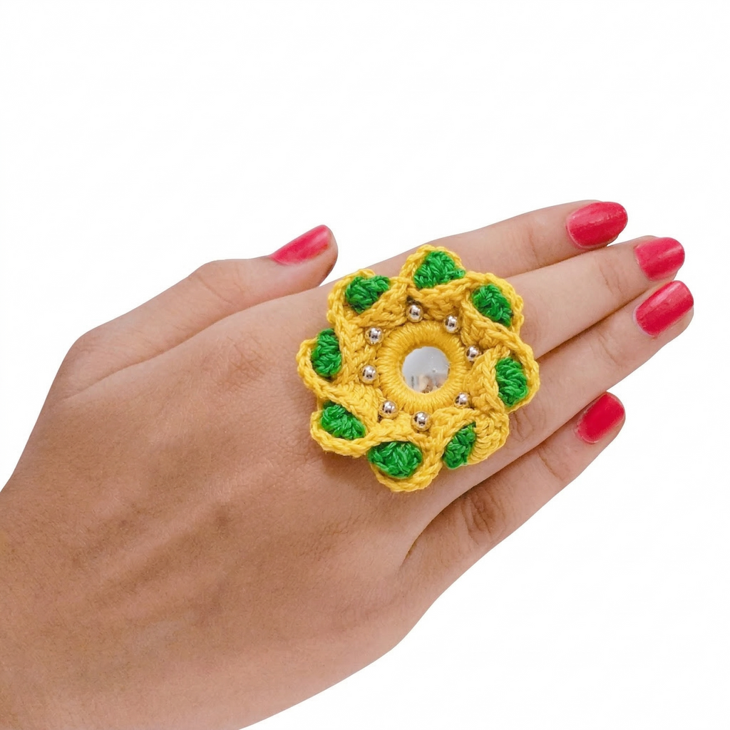 Yellow and green handmade crochet flower ring with center mirror and silver beads worn on a hand.