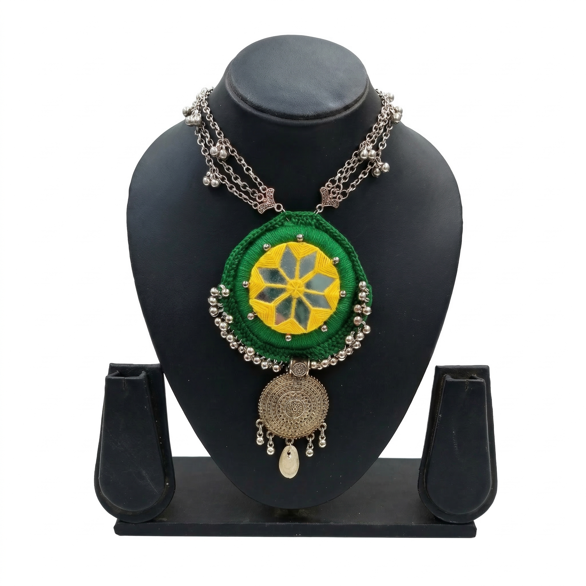 Green fabric mandala necklace with yellow mirror work and oxidized silver charms on a black display stand.
