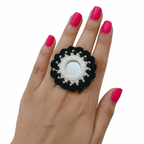 Adjustable handmade black and white crochet finger ring featuring a central round mirror and silver bead detailing on a model's hand.