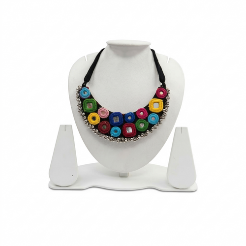 Handmade black fabric choker necklace featuring colorful embroidered circles, inlaid mirrors, and silver bead trim on a white display stand.