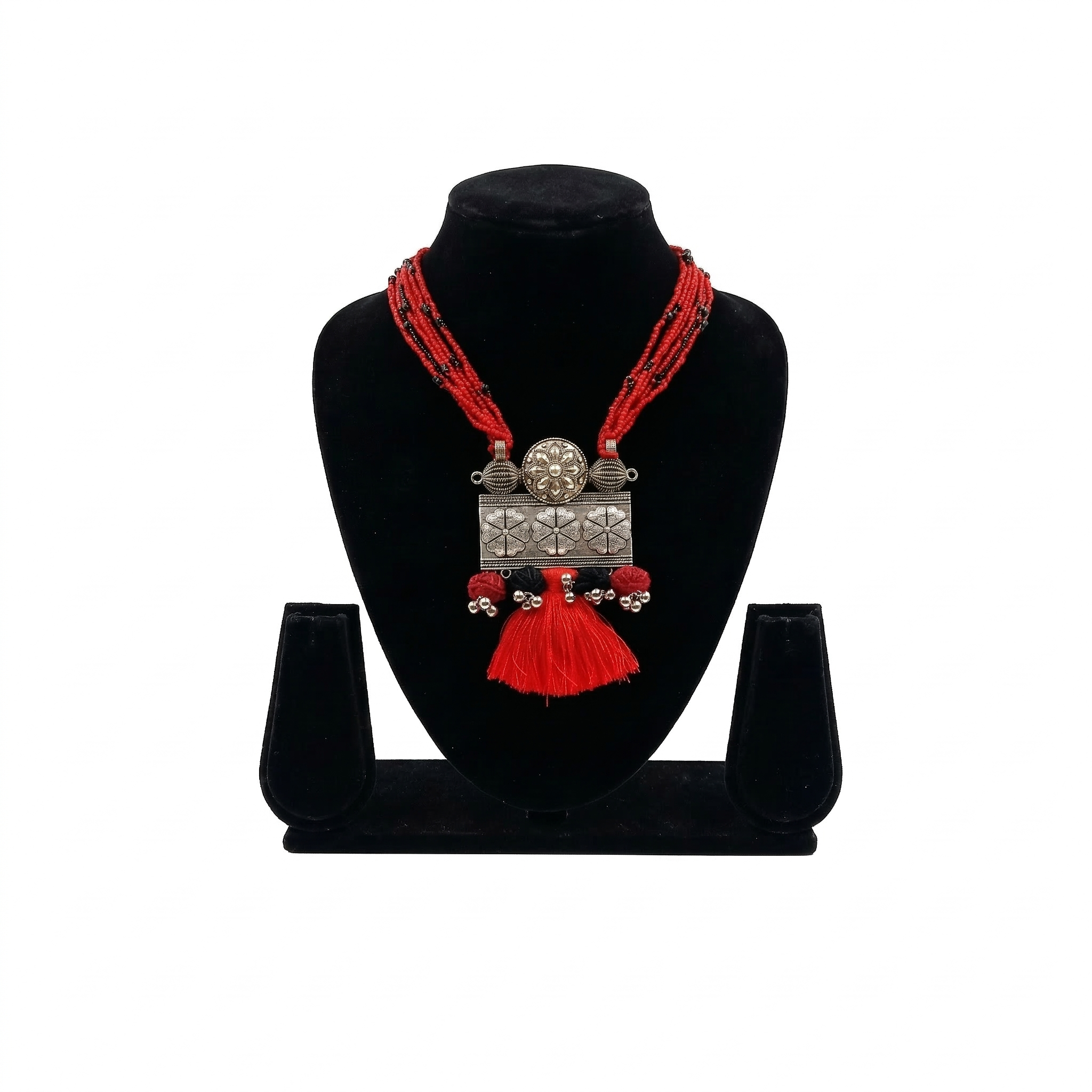 Oxidized silver floral pendant necklace with multiple rows of red seed beads and a red tassel, displayed on a black jewelry bust against a white background.