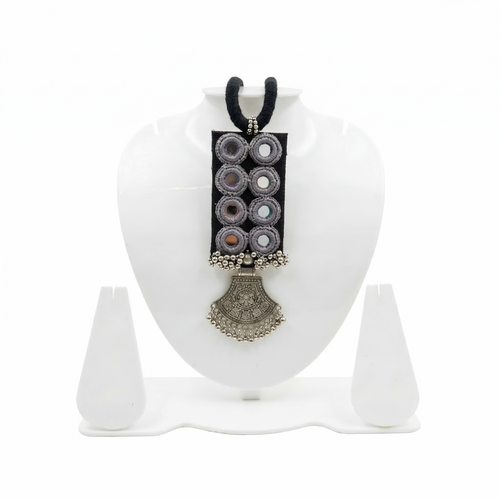 Handmade black fabric choker necklace featuring traditional mirror work embroidery and a vintage-style oxidized silver pendant on a white jewelry display stand.