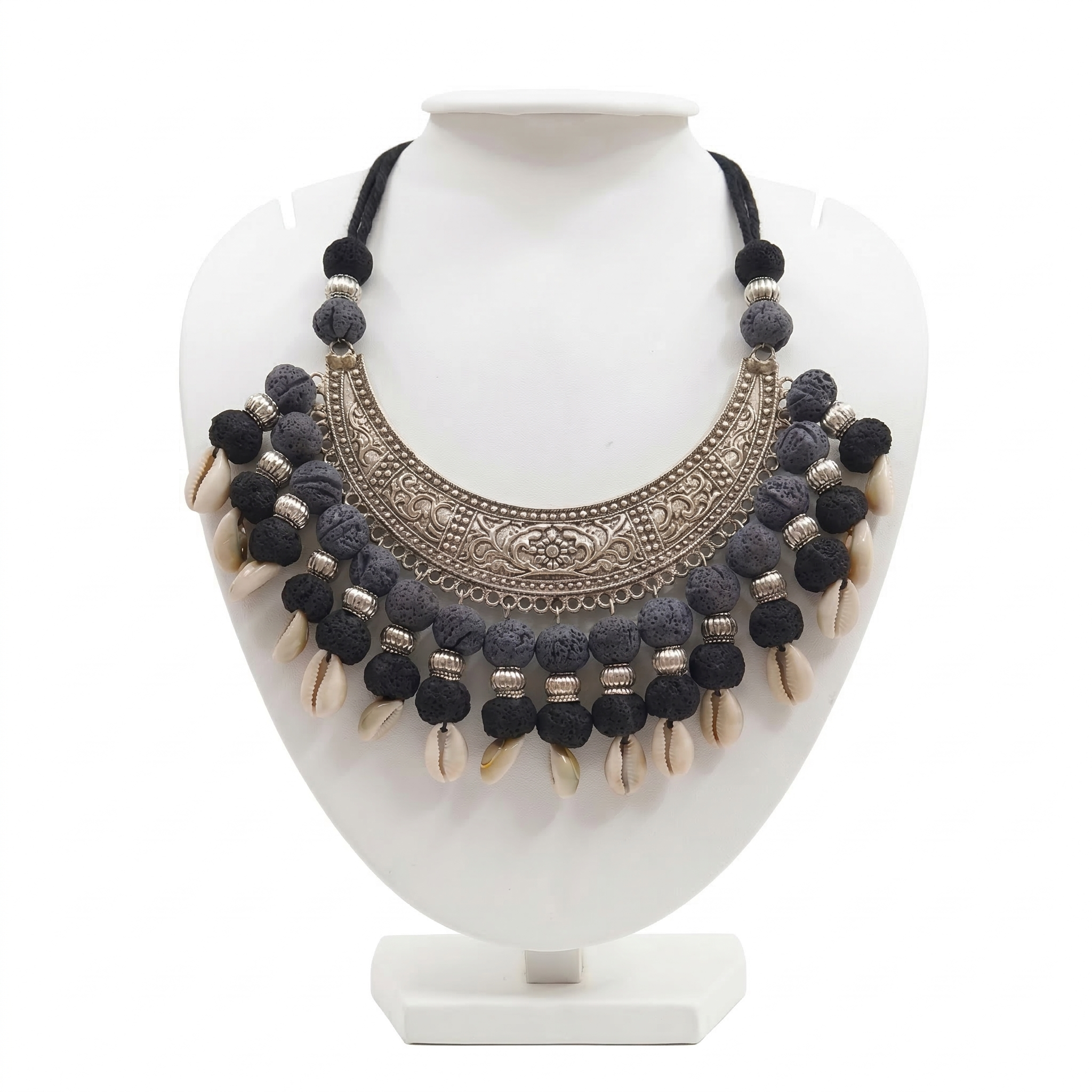Handcrafted tribal statement necklace on a white display stand featuring a large oxidized silver crescent pendant, textured black beads, and dangling cowrie shells.