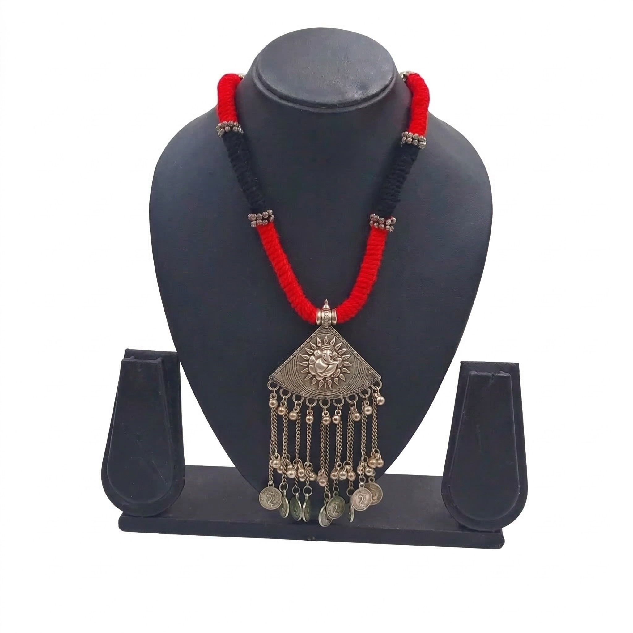 Oxidized silver pendant necklace on red and black braided thread with coin tassels and sun motif on a black display stand.