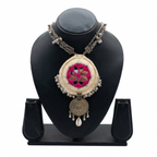 Tribal style handcrafted necklace with pink mirror embroidery and silver charms on a black jewelry bust display.
