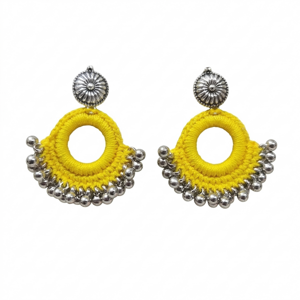 Pair of bright yellow silk thread crochet hoop earrings featuring silver oxidized floral studs and hanging metal ghungroo beads on a white background.