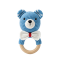 A 4K photorealistic blue crochet bear baby rattle with a white bow tie and natural wooden teething ring on a solid white background.