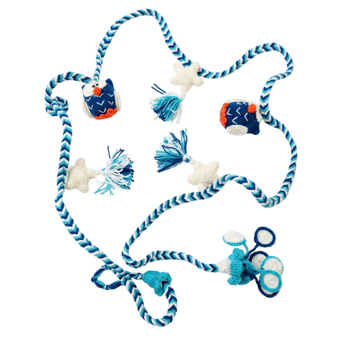 A handcrafted crochet garland featuring blue owls, white stars, and blue-toned tassels on a chevron-patterned rope against a white background.