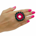 Handcrafted circular fabric ring featuring traditional mirror work, pink embroidery, and black crochet border on a model's hand.