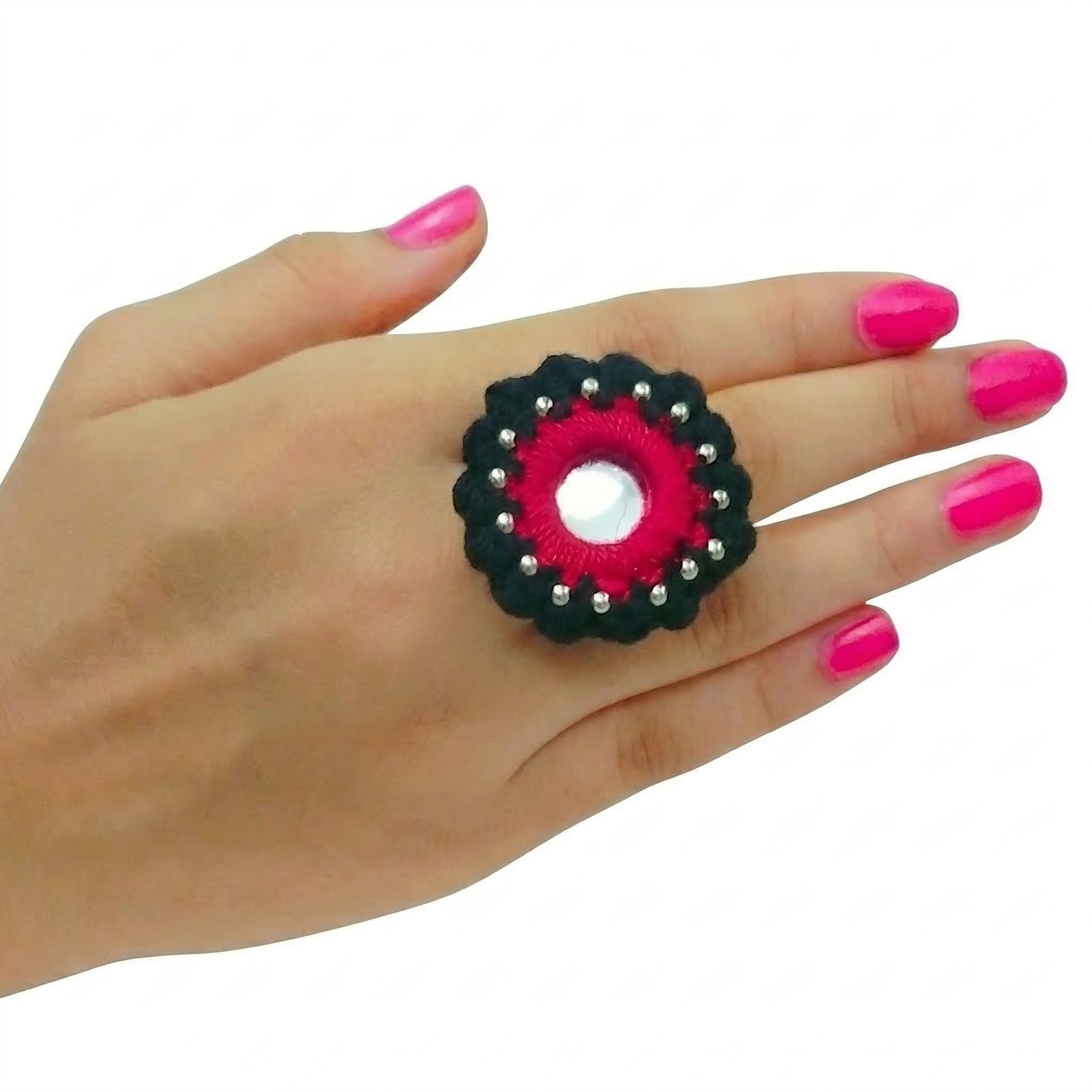 Handcrafted circular fabric ring featuring traditional mirror work, pink embroidery, and black crochet border on a model's hand.