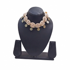 Boho-style cream cowrie shell choker necklace featuring gold-tone coin charms on a black display stand.
