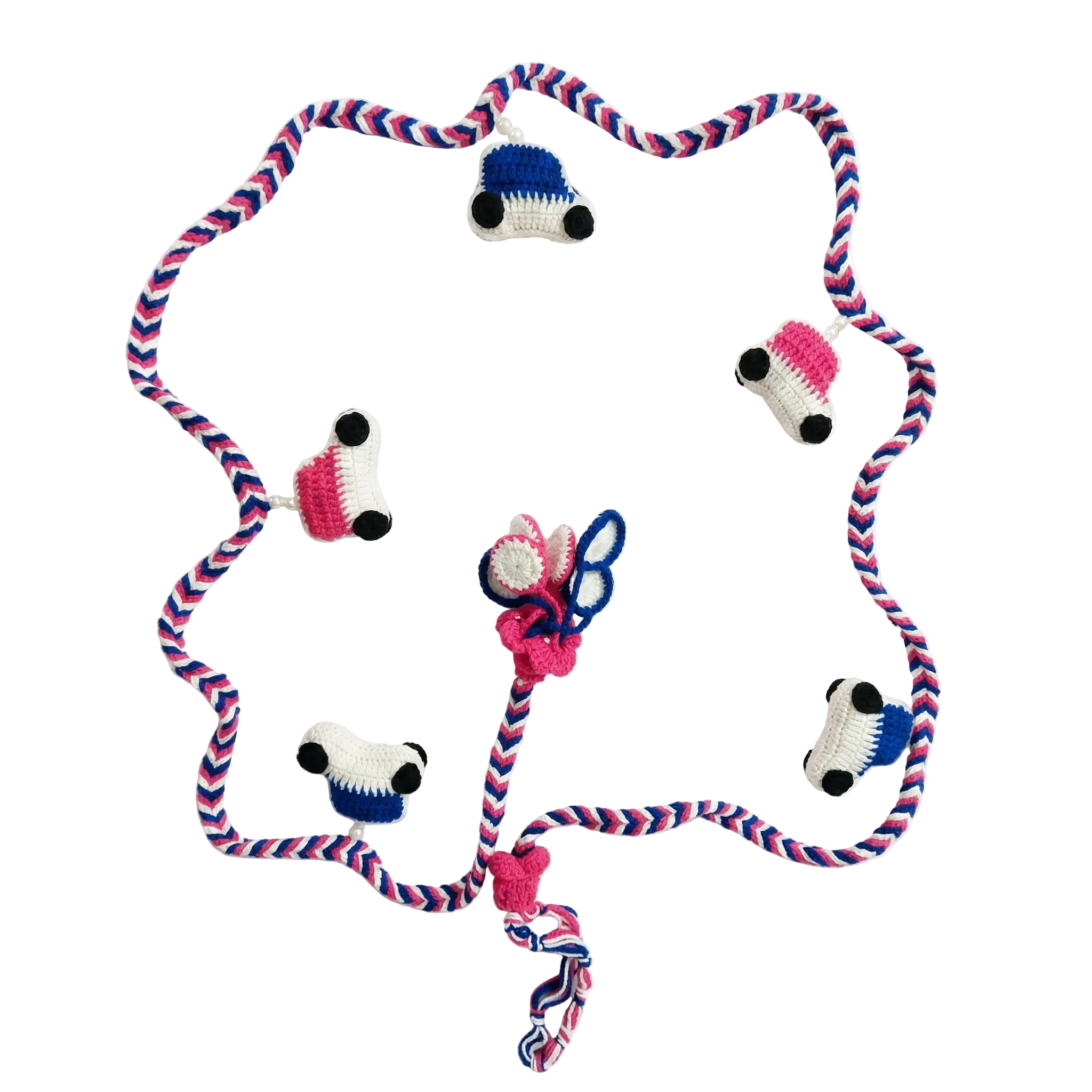 High-quality overhead shot of a handmade crochet garland featuring small blue and pink cars on a braided chevron string against a white background.