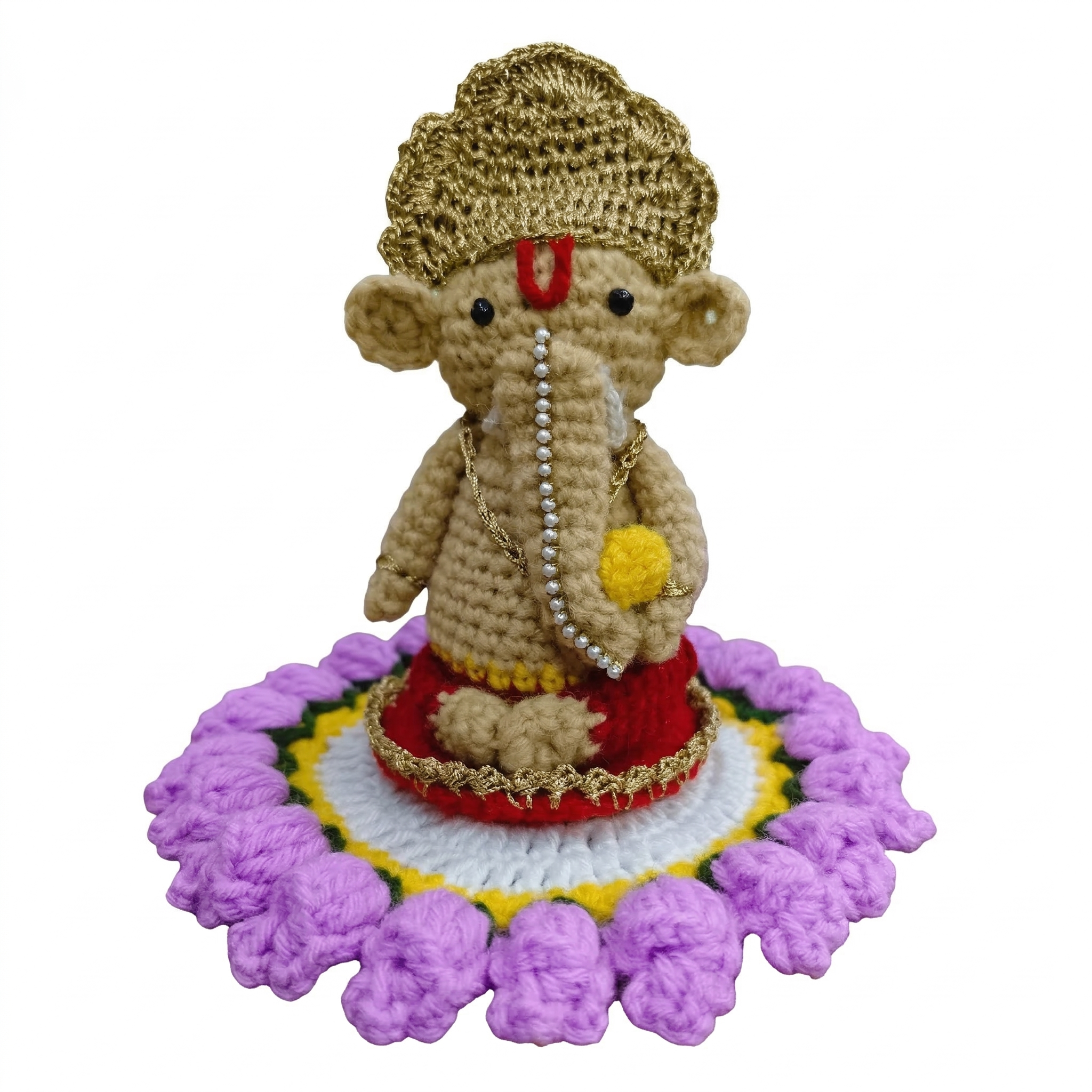 Miniature crochet Ganesha figurine with golden crown and pearl details sitting on a purple and white knitted lotus base, isolated on a white background.