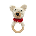 Crochet white polar bear baby rattle with red bow tie on natural wooden teething ring, isolated on white background.