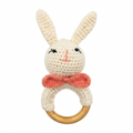 White crochet bunny baby rattle with pink bow on wooden ring.