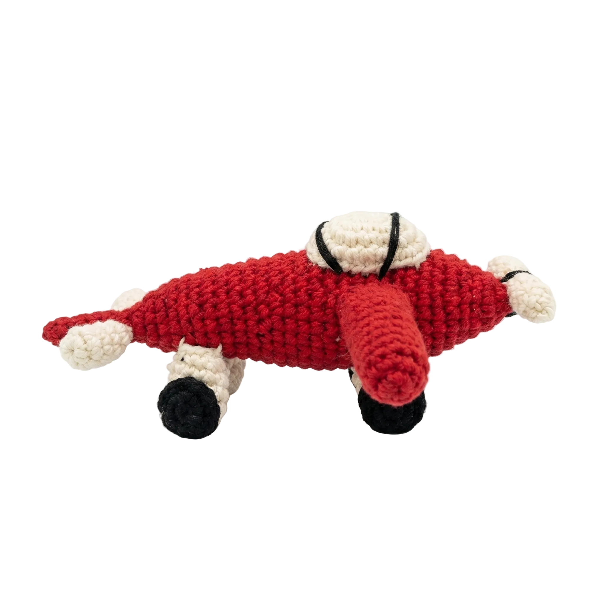 studio shot of a red and cream crochet airplane plush with black wheels on a solid white background.