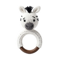 White and grey crocheted zebra baby rattle toy attached to a smooth dark wood teething ring, isolated on a white background.