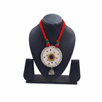 Traditional white circular embroidered pendant necklace with red thread cord and silver jhumka charm on a black jewelry bust.