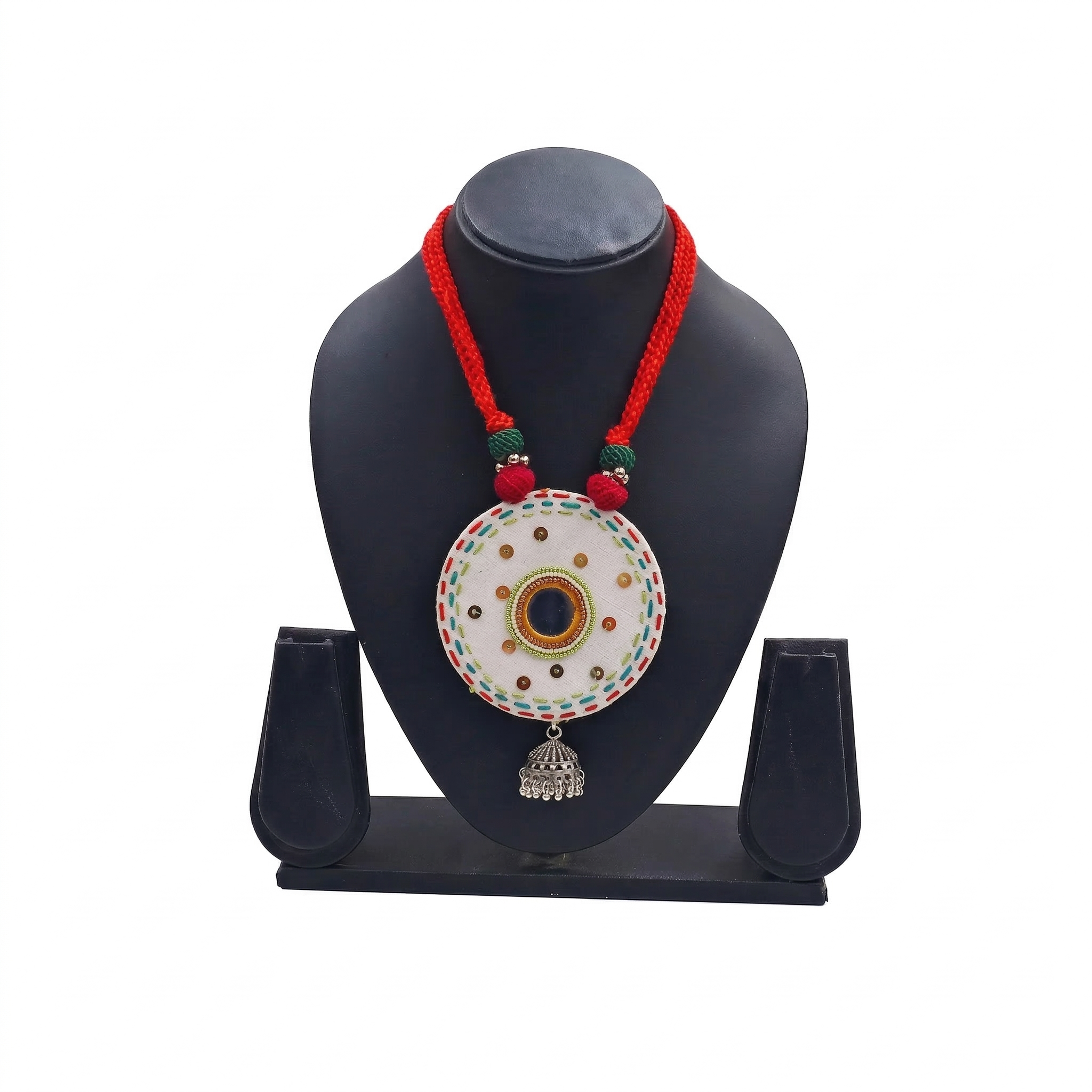 Traditional white circular embroidered pendant necklace with red thread cord and silver jhumka charm on a black jewelry bust.