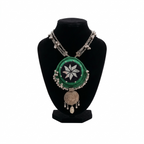 Traditional Indian-style green crochet pendant necklace with mirror work and silver bead trim on a black display stand.