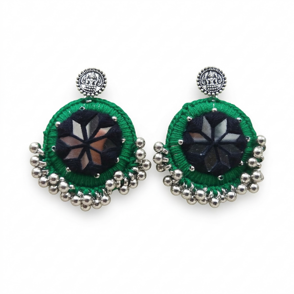 Pair of round green thread-work earrings featuring central star-shaped mirror inlay and silver metallic bead accents on a white background.