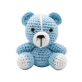 Small handmade light blue and white crochet teddy bear sitting against a plain white background, featuring black safety eyes and a stitched nose.
