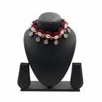 Handmade maroon crochet choker necklace featuring white cowrie shells and hanging silver bohemian coin charms on a black display stand.