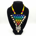 Handmade triangular black fabric necklace featuring colorful mirror embroidery, cowrie shells, and a silver bird-motif pendant on a black mannequin.