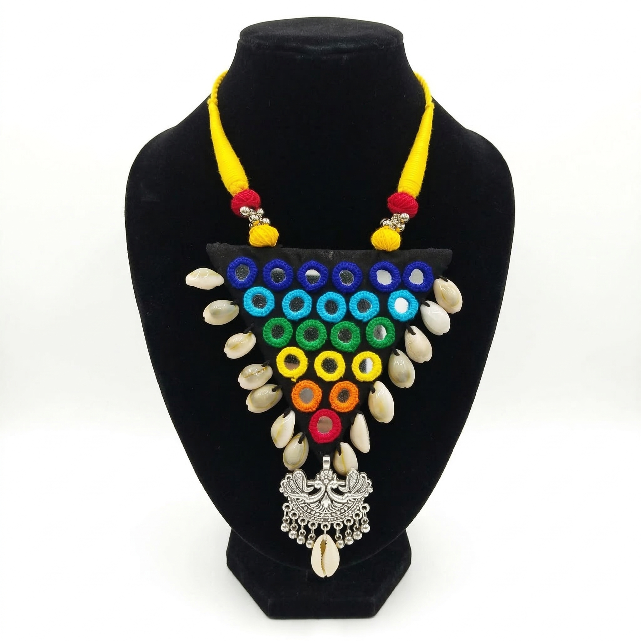Handmade triangular black fabric necklace featuring colorful mirror embroidery, cowrie shells, and a silver bird-motif pendant on a black mannequin.