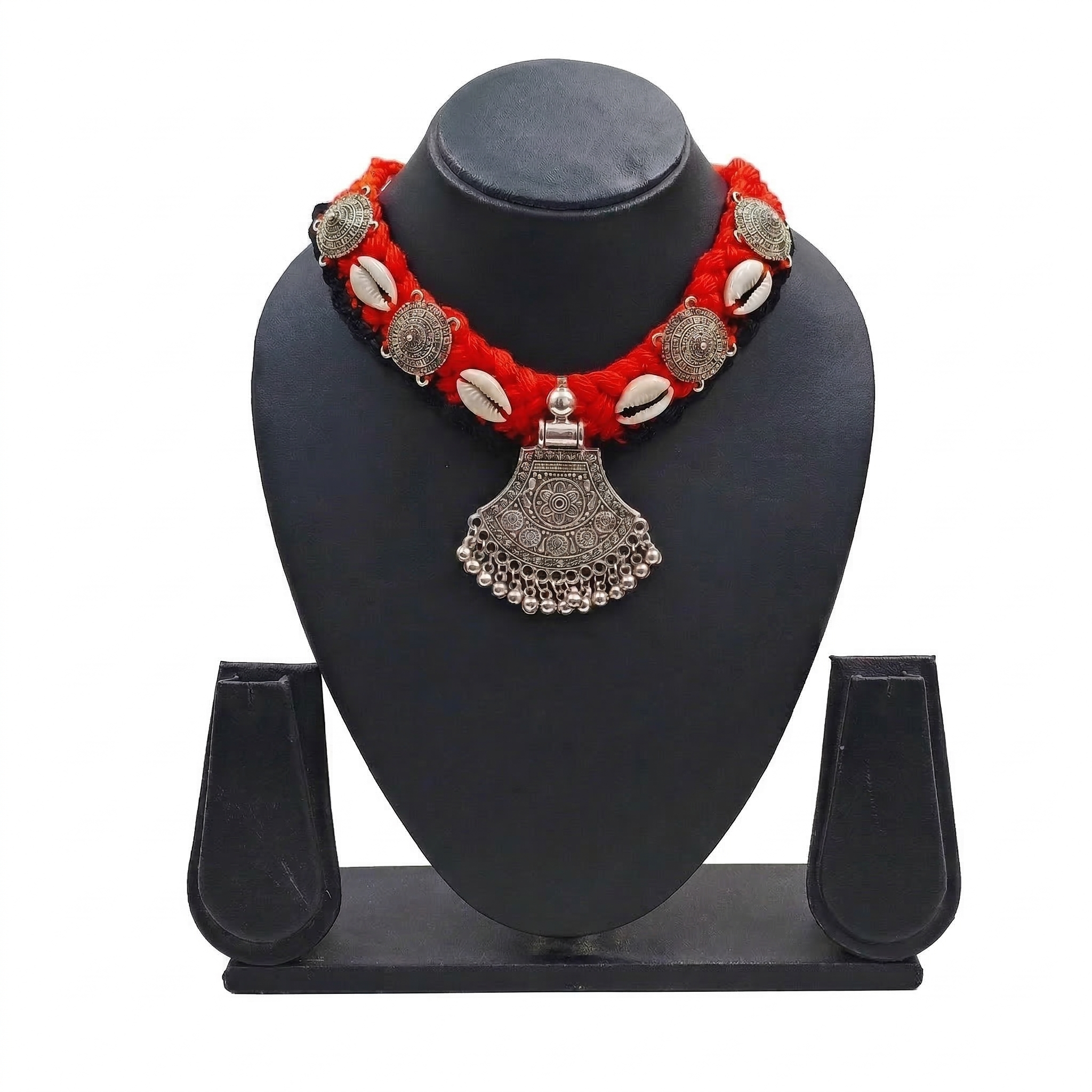 Traditional Indian oxidized silver pendant necklace on a red braided thread with cowrie shell accents and tribal metal charms, displayed on a black jewelry bust.