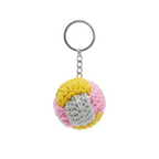 A round, handmade crochet keychain featuring a patchwork design of yellow, pink, and grey yarn on a white background.