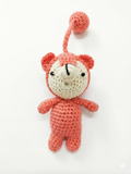 handmade pink and cream crochet teddy bear with a matching yarn loop attachment, isolated on a pure white background.