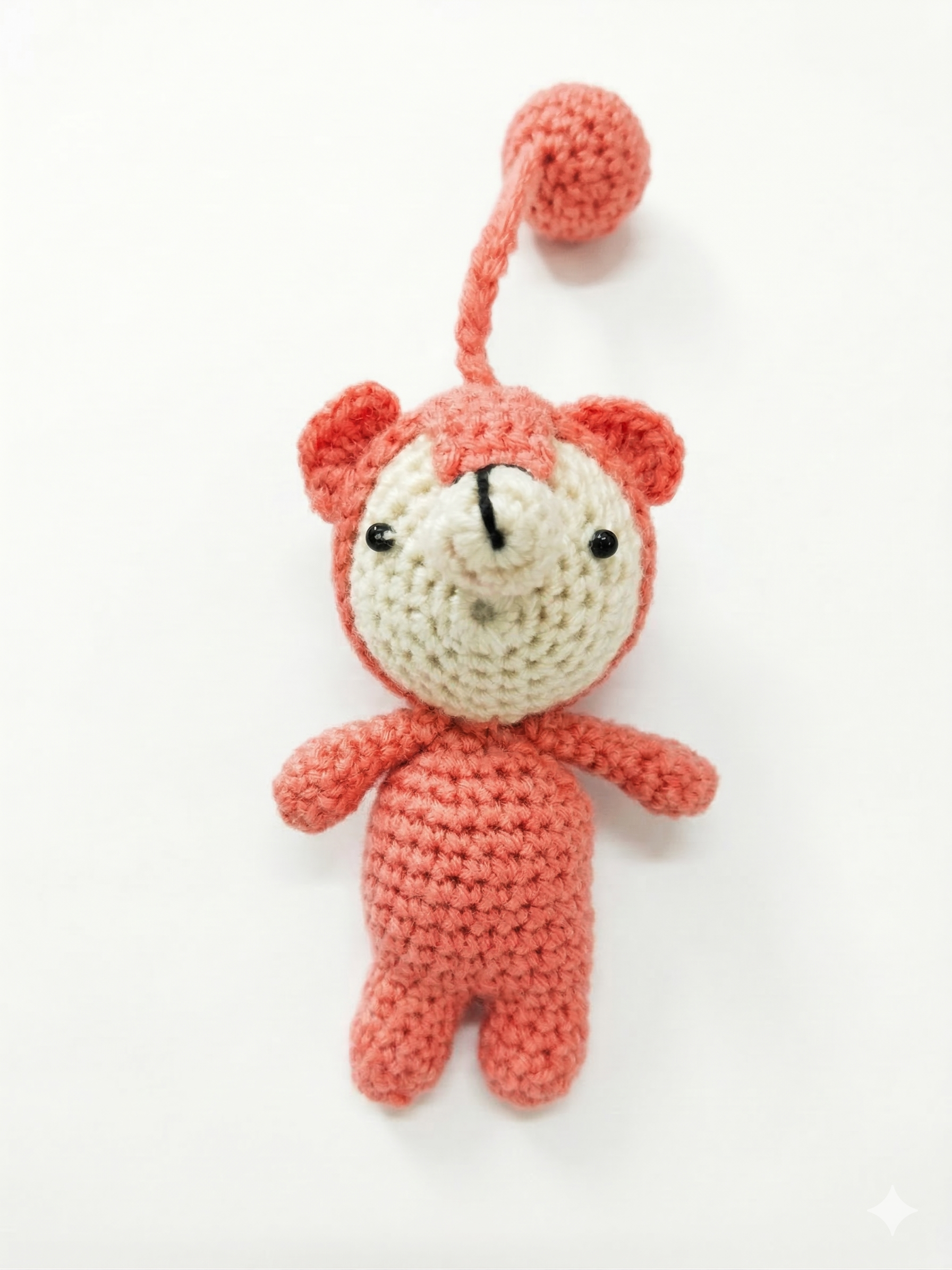 handmade pink and cream crochet teddy bear with a matching yarn loop attachment, isolated on a pure white background.