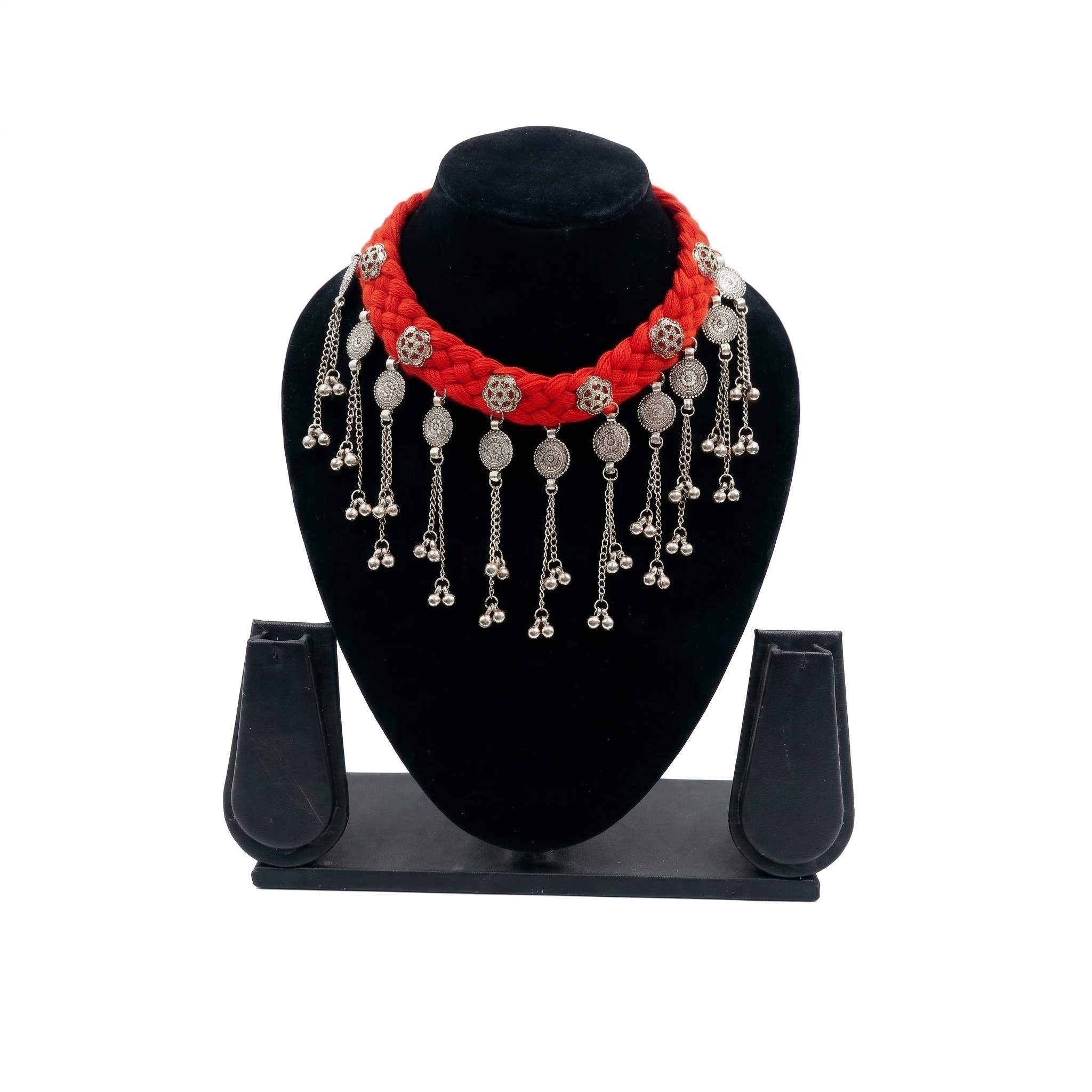 Red braided fabric choker necklace on a black display stand featuring hanging oxidized silver coins and ghungroo bells.