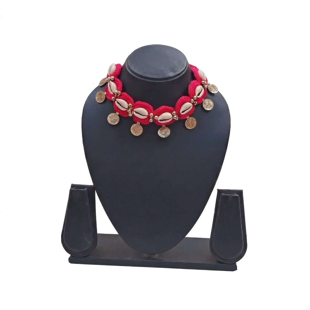 Red crochet choker necklace featuring white cowrie shells and hanging gold coin charms on a black display stand.