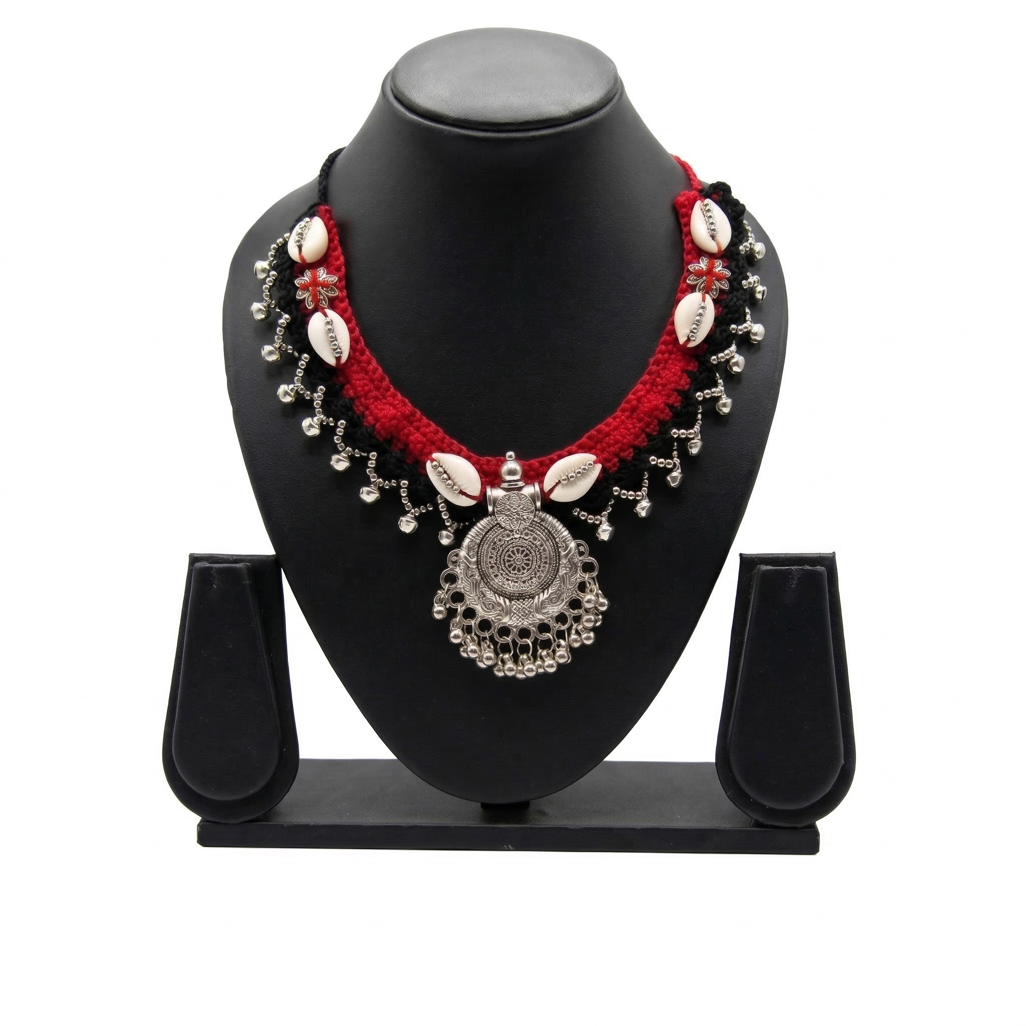 Traditional handcrafted red and black crochet necklace with cowrie shells and oxidized silver pendant on a display stand.
