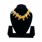 Yellow crochet choker necklace featuring white cowrie shells and hanging silver engraved coins on a black display stand.