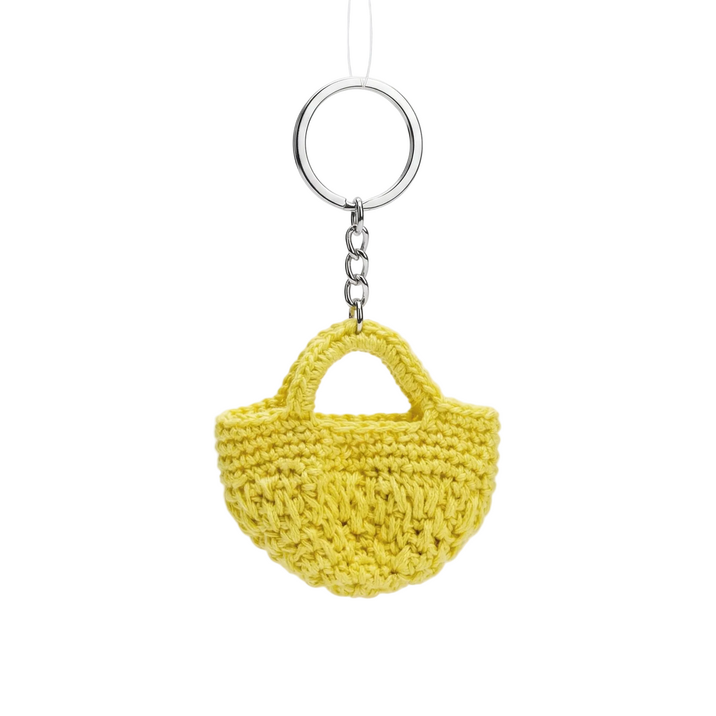 A small, bright yellow crochet tote bag keychain with a silver ring against a clean white background.
