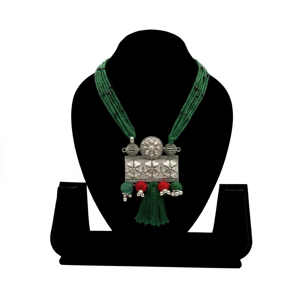 Handcrafted oxidized silver rectangular floral pendant on a layered green silk thread necklace with red accents and tassel.