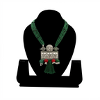 Handcrafted oxidized silver rectangular floral pendant on a layered green silk thread necklace with red accents and tassel.