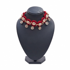 Red handmade crochet choker necklace featuring white cowrie shells, gold beads, and dangling silver-tone coin charms on a black display stand.