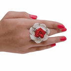 Handmade white crochet flower ring featuring a red satin ribbon rose center and silver bead details on a model's hand.
