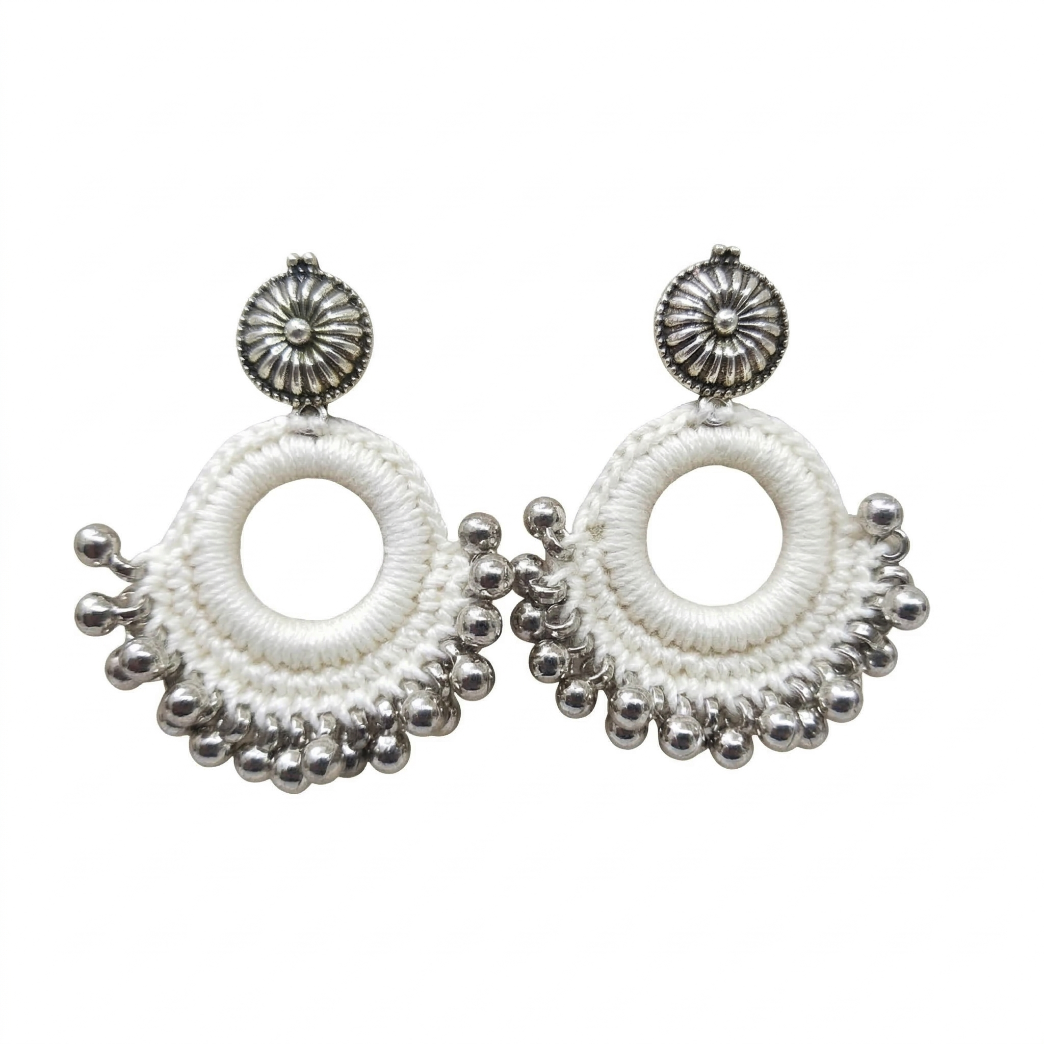 Pair of handmade white silk thread crochet hoop earrings featuring silver oxidized floral studs and dangling metallic ghungroo beads on a white background.